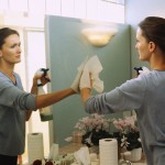 Spring Clean Your Life shown by woman cleaning mirror