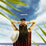 Young woman watching airplane fly by from tropical beach --- Image by © Royalty-Free/Corbis